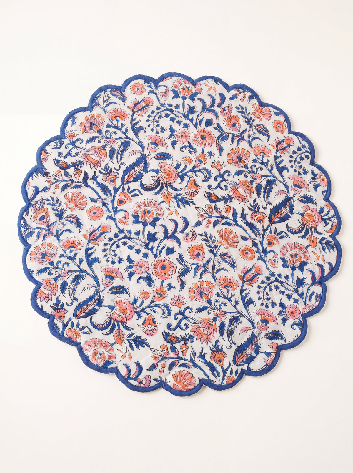 Coral Garden round quilted placemat with coral and blue floral print and blue scalloped edge