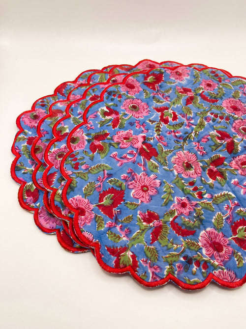 Stack of four Berry Meadow quilted floral placemats with red scalloped borders
