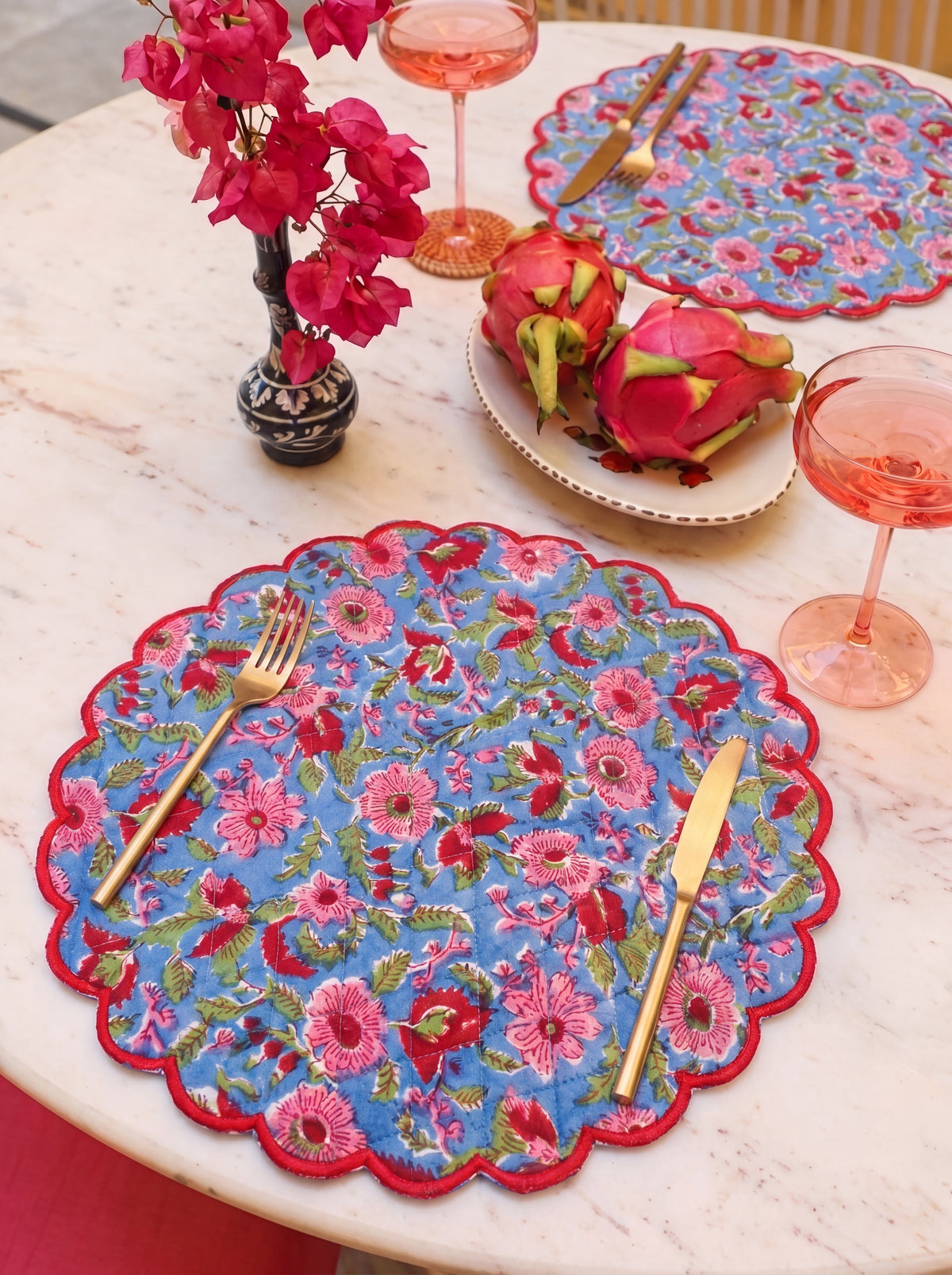 Berry Meadow floral scalloped placemats styled with gold flatware on a dining table