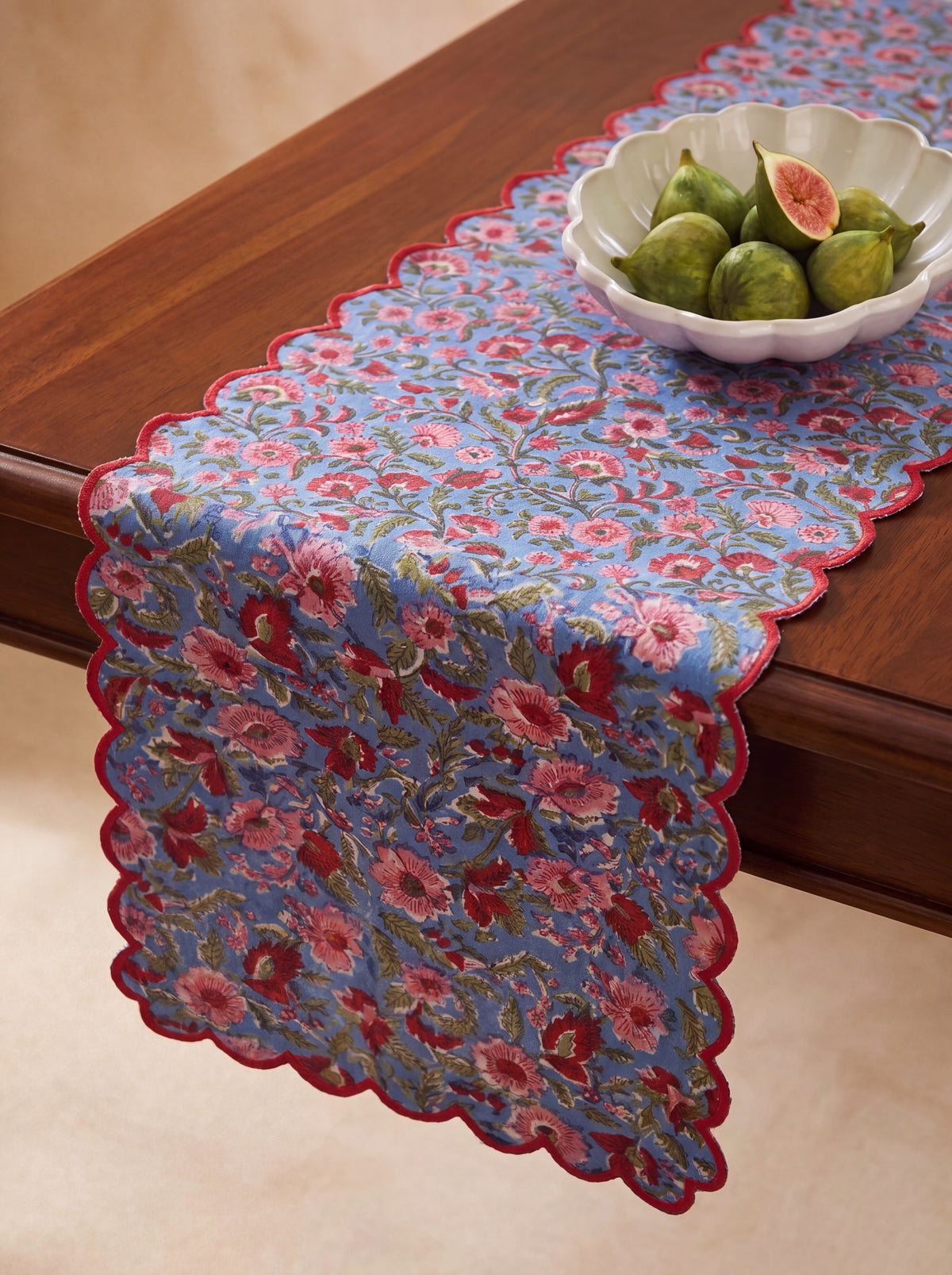 Berry Meadow floral table runner styled on a wooden dining table with red scalloped border