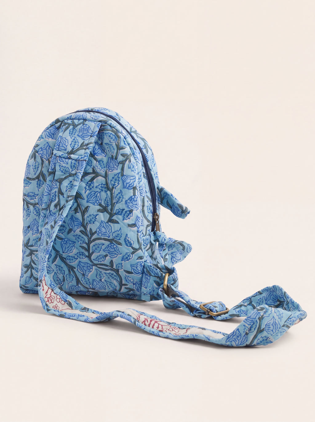 Side and back view of Fabalore Blue Bloom sling backpack showing the adjustable fabric strap and quilted construction.