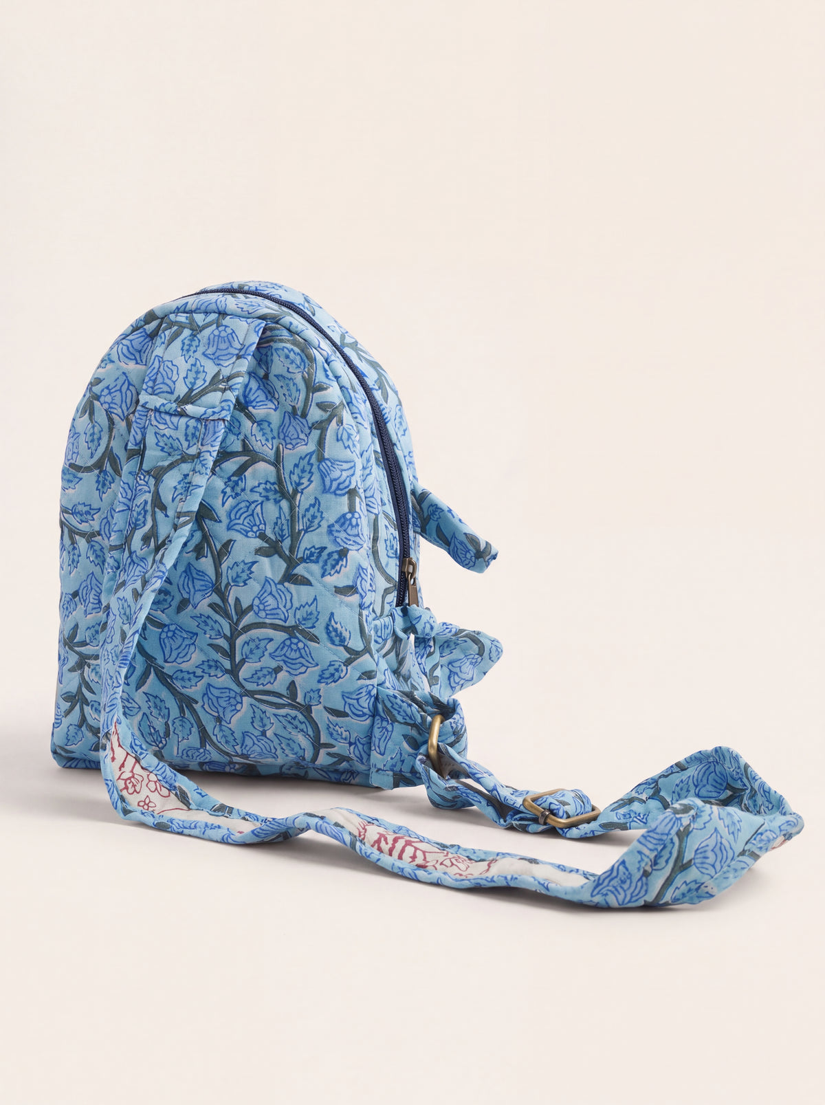 Side and back view of Fabalore Blue Bloom sling backpack showing the adjustable fabric strap and quilted construction.