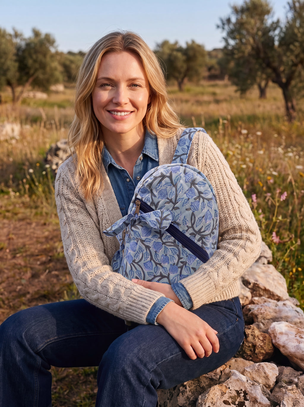 Woman holding a Fabalore Blue Bloom quilted sling backpack outdoors in a natural setting.