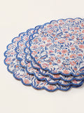 Stack of Coral Garden scalloped quilted placemats with blue embroidered edging