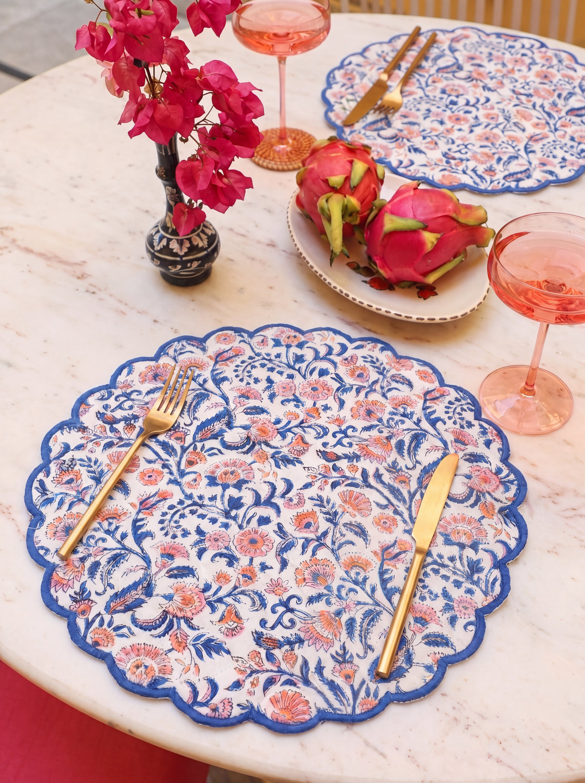 Coral Garden floral placemat styled on a dining table with gold flatware and pink glassware