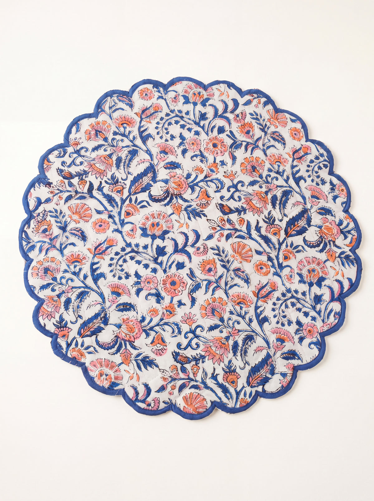 Coral Garden round quilted placemat with coral and blue floral print and blue scalloped edge
