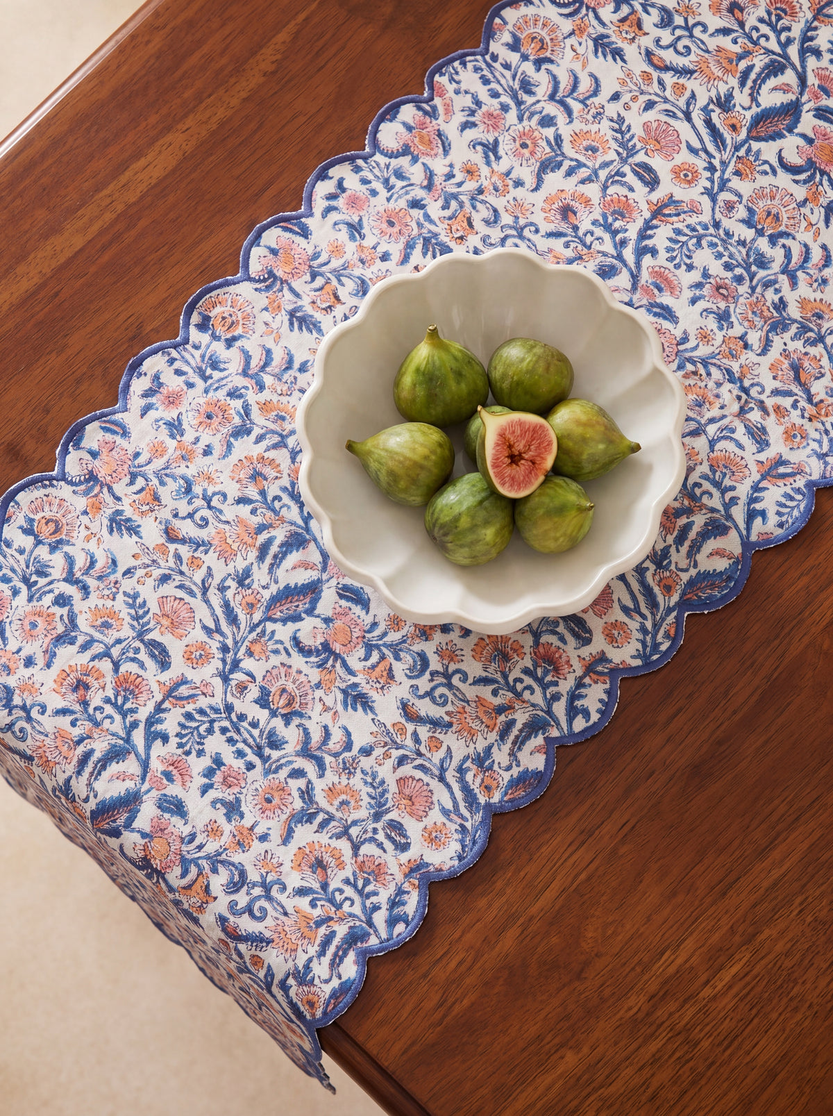 Coral Garden floral cotton table runner styled on a wooden dining table with scalloped blue border