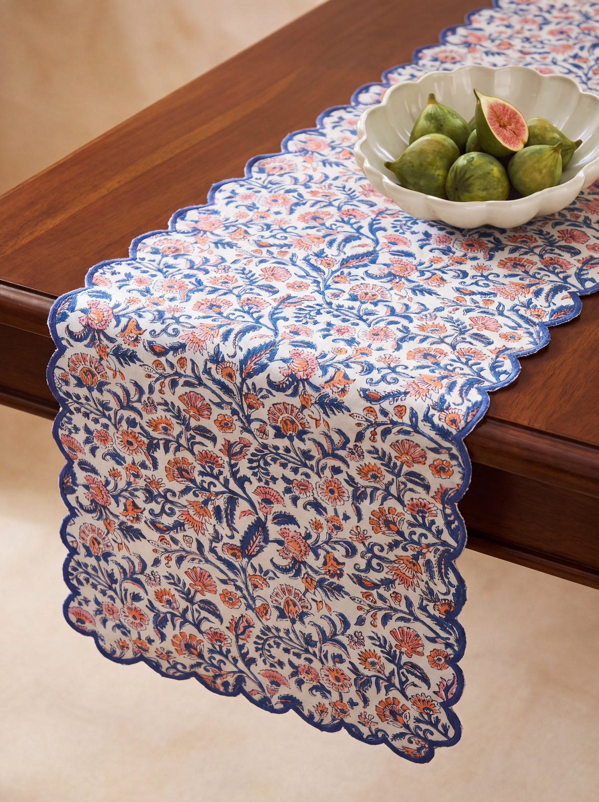 Coral Garden floral cotton table runner styled on a wooden dining table with scalloped blue borde