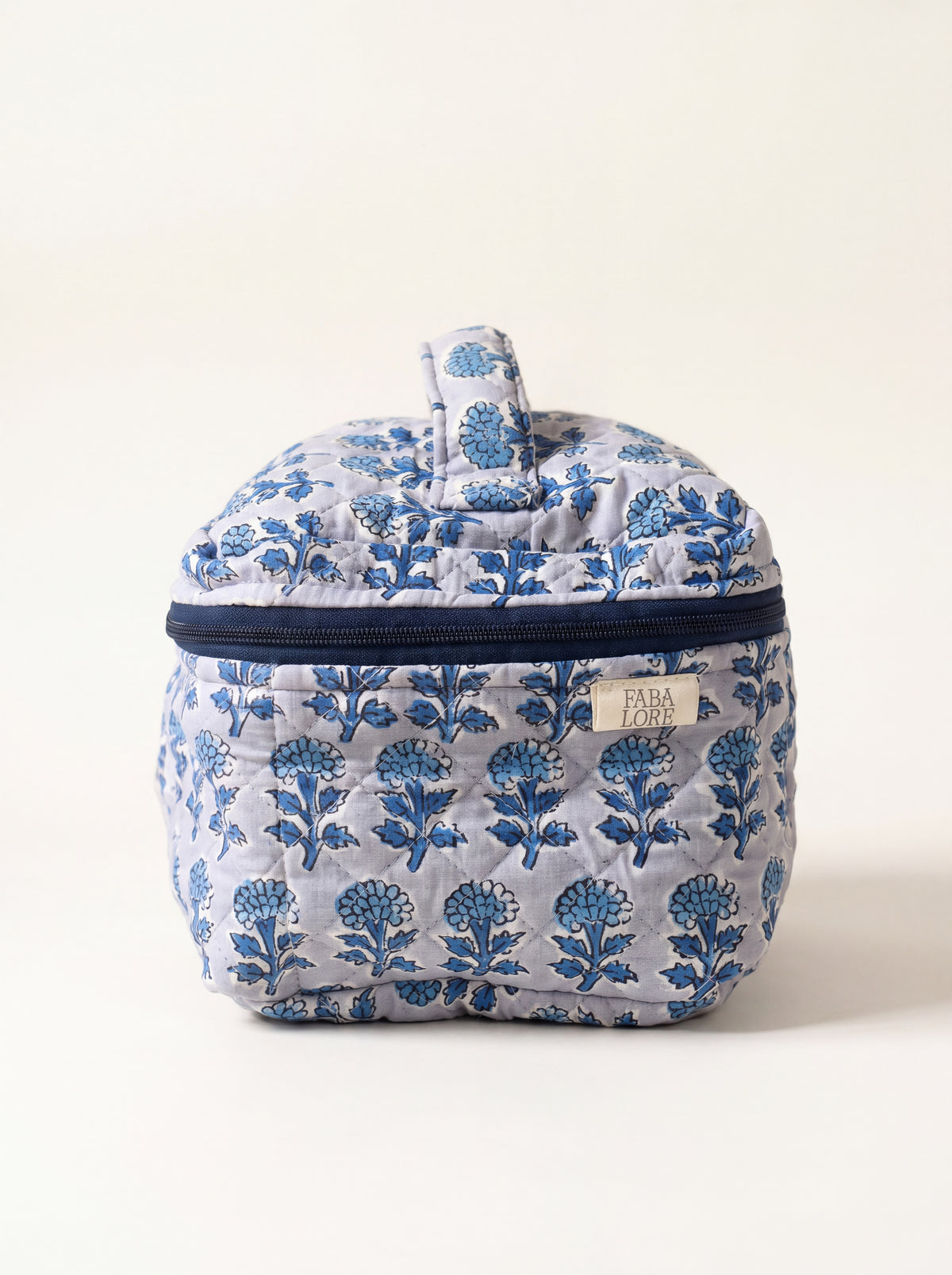 Indigo Bloom quilted floral vanity case showing structured shape, top handle and navy zip-around closure.