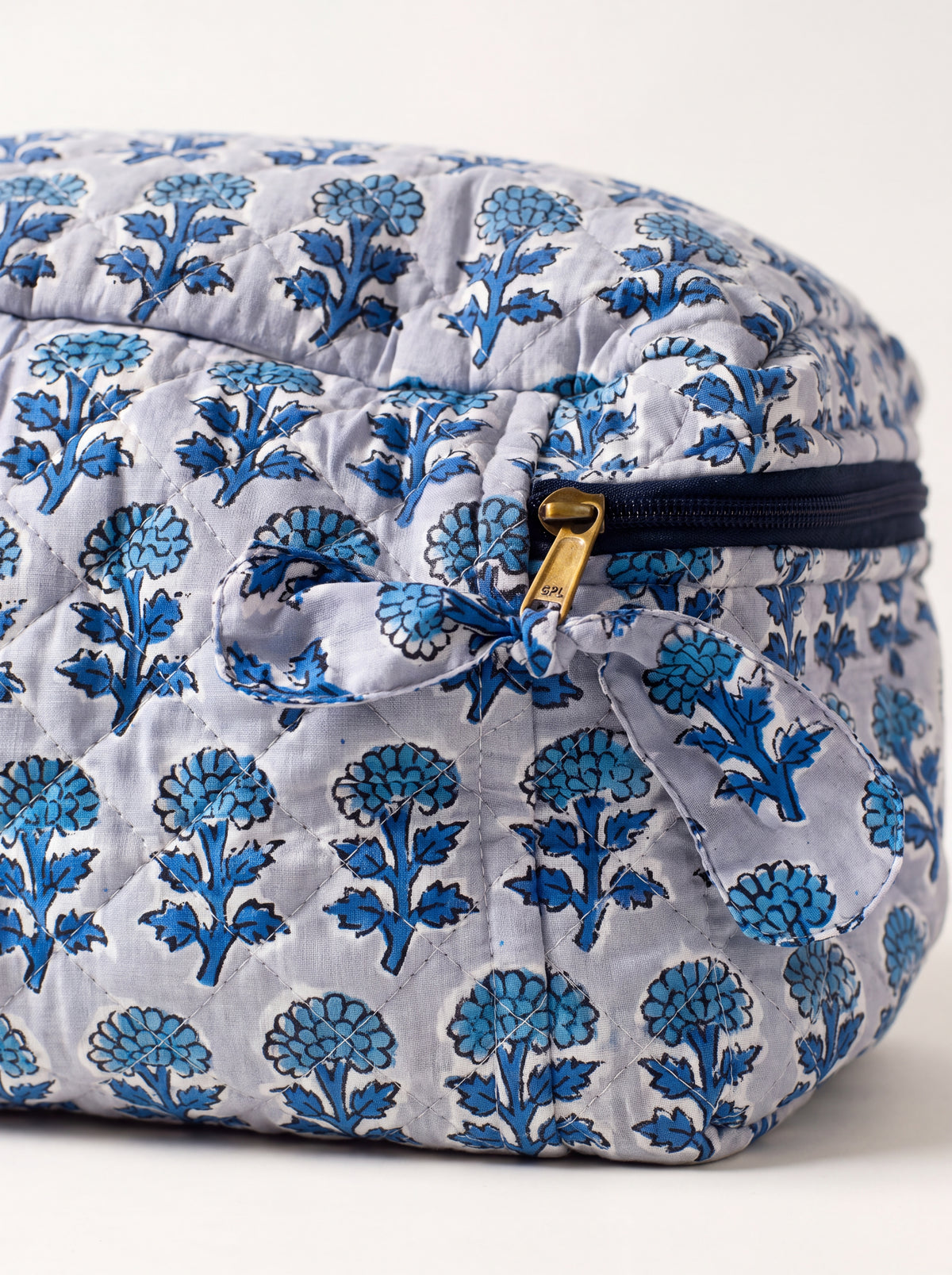 Close-up of Fabalore Indigo Bloom vanity case showing quilted floral fabric, zipper and fabric zipper pull.