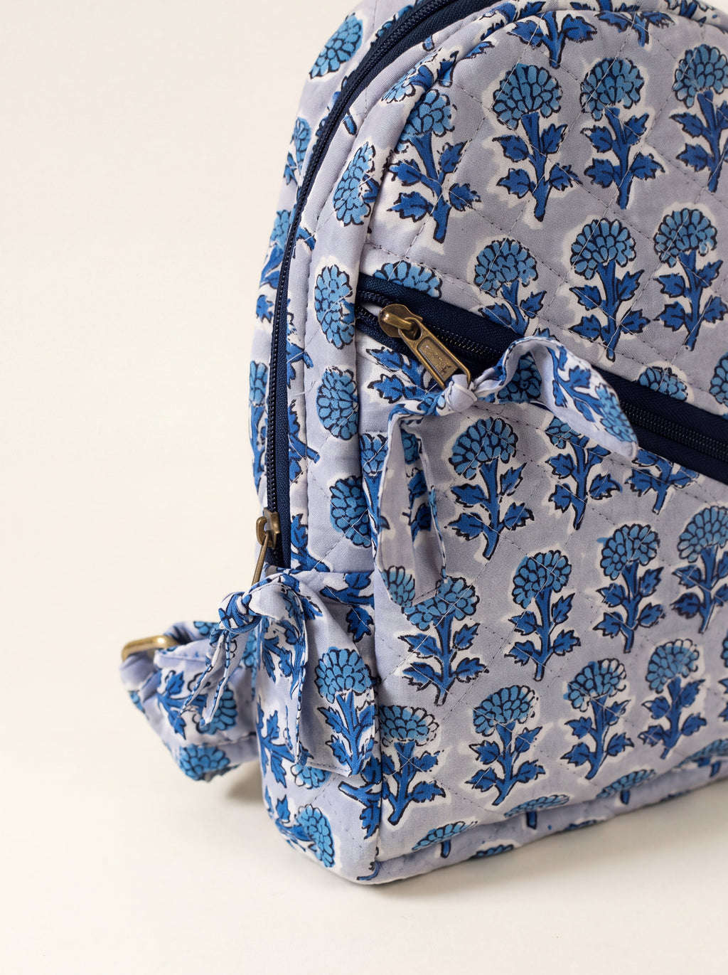 Close up of Fabalore Indigo quilted cotton backpack showing the blue floral print, front zipper pocket and fabric tie detail.