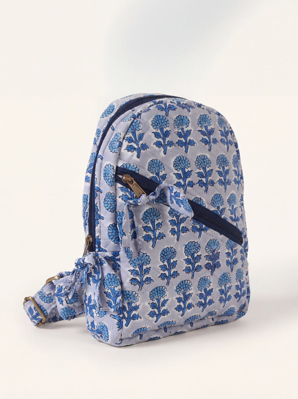 Front product view of the Fabalore Indigo quilted cotton backpack with diagonal navy zipper pocket and floral print.