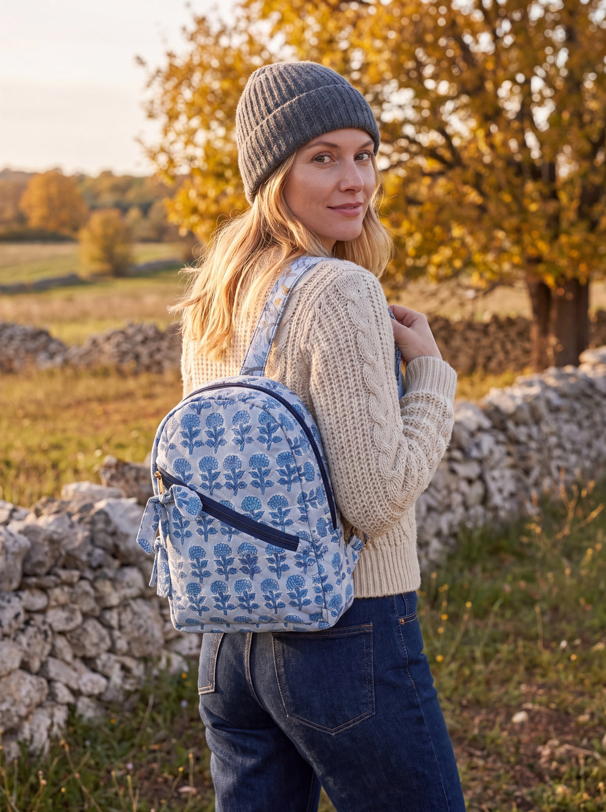 Woman wearing the Fabalore Indigo quilted cotton backpack outdoors with a cream sweater and knit hat.