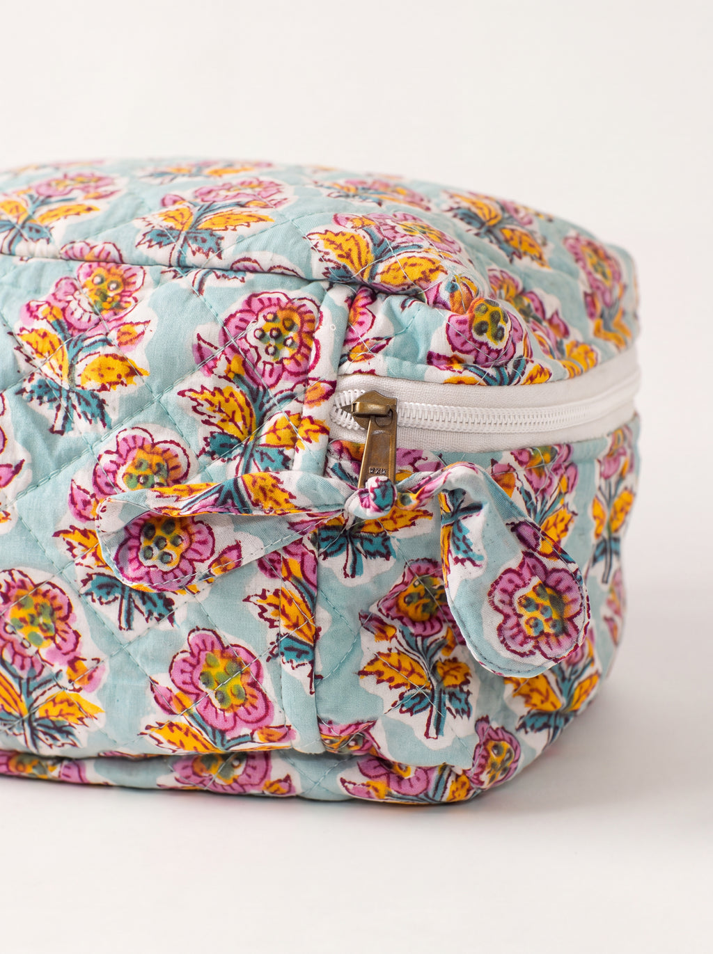 Close up of Fabalore Marigold Bloom vanity case showing quilted floral fabric, zipper and fabric zipper pull.