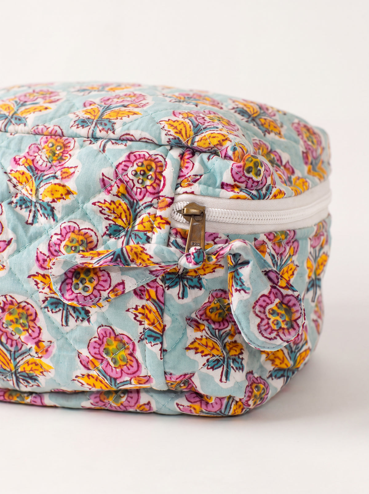 Close up of Fabalore Marigold Bloom vanity case showing quilted floral fabric, zipper and fabric zipper pull.