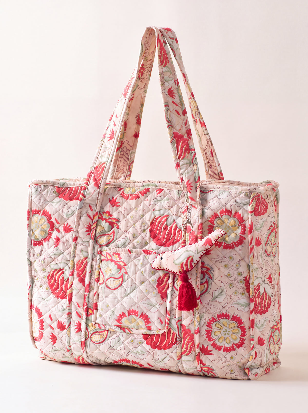 Fabalore Meadow quilted tote bag in a red, sage green and beige botanical print with exterior pockets and fabric charm.