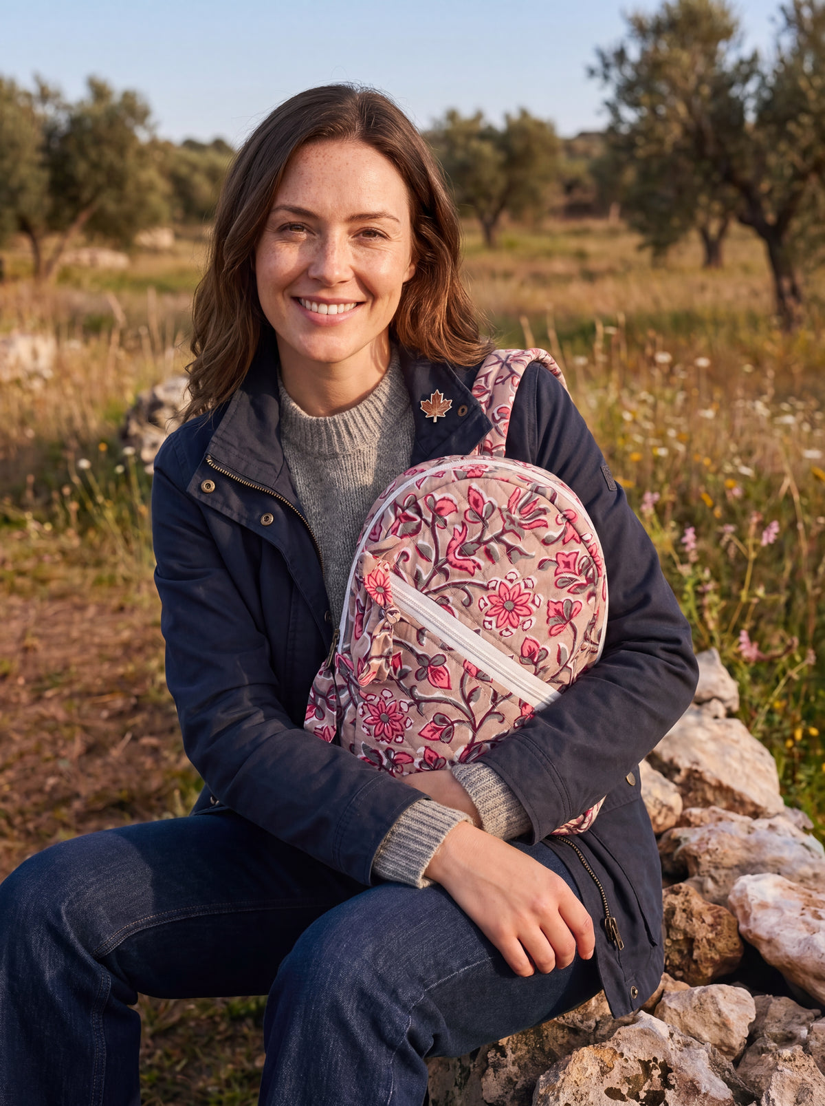 Woman carrying the Rosewood quilted floral backpack outdoors in a fall setting.