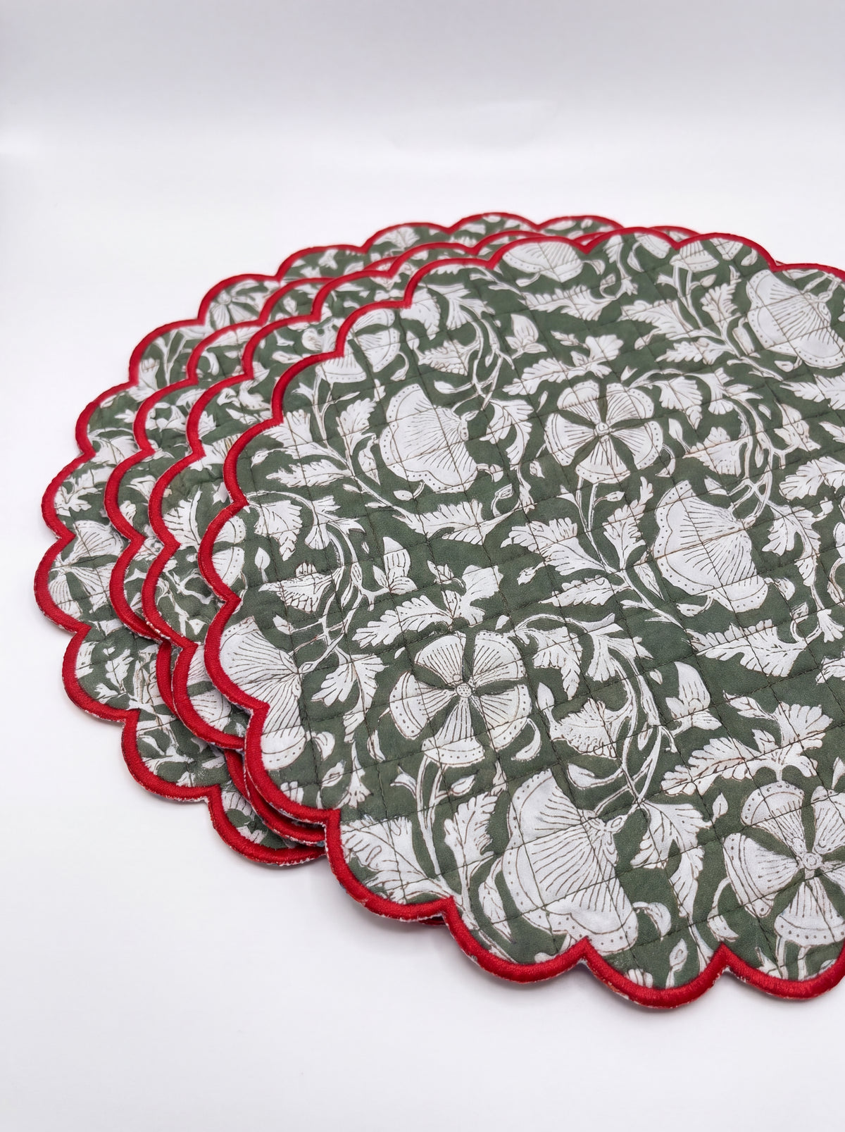 Stack of four Woodland Vine quilted cotton placemats with red scalloped borders